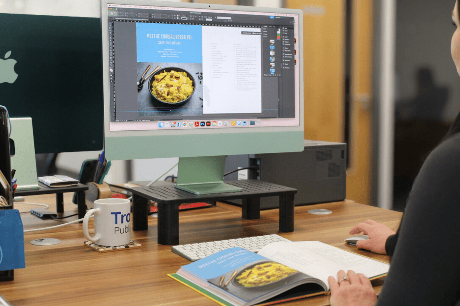 A designer typesetting a cookery book on a large monitor